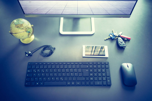 Workplace of a freelancer: Arrangement of computer, keyboard, earphones, keys and globe - Zdjęcie, obraz