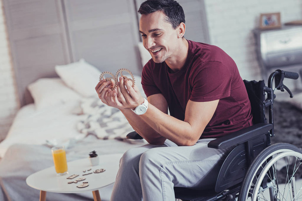Cheerful disabled man comparing the wooden wheels - Фото, зображення