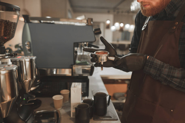 バリスタ コーヒーとプロのコーヒー マシンのコーヒーを準備するための準備とホルダーを保持します。バーテンダーは、portafilter を手で保持して、コーヒーを準備します。コーヒーのコンセプト - 写真・画像