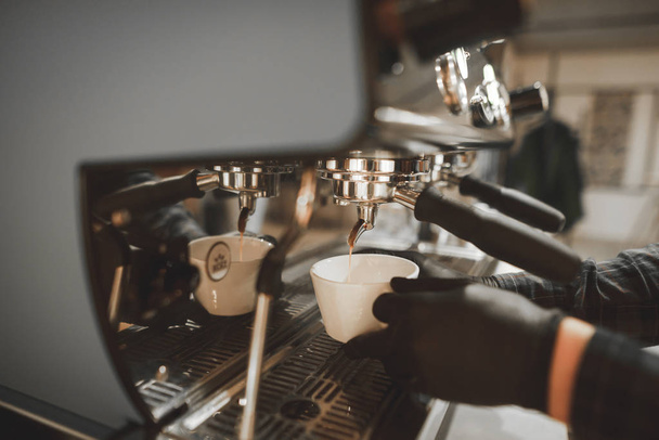 Крупным планом фото процесса приготовления кофе на профессиональной кофеварке в кафе, наливая кофе наливает в cup.Barista наливает эспрессо в чашку кофе machine.Background. Copyspace
 - Фото, изображение