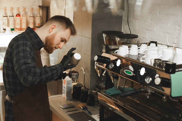Взвешивание зерна кофе в цифровом масштабе. Руки мужчины-баристы наливают жареные зерна кофе на паперкап и весы перед варкой кофе
. - Фото, изображение