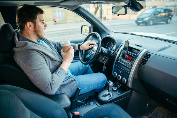 θυμωμένος άνθρωπος οδήγηση αυτοκινήτου και να πίνει καφέ. κατάρρευση της κυκλοφορίας. τρόπος ζωής - Φωτογραφία, εικόνα