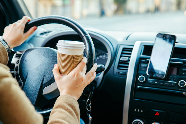 Kobieta, prowadzenie samochodu i picia kawy. Nawigacja za pomocą telefonu. styl życia - Zdjęcie, obraz