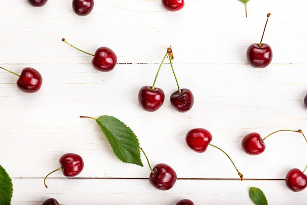 sweet red cherries scattered on a white wooden background. space for tex - Foto, Imagen