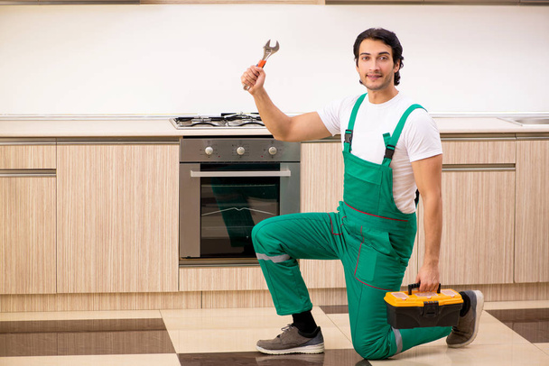 jeune entrepreneur réparer four dans la cuisine  - Photo, image