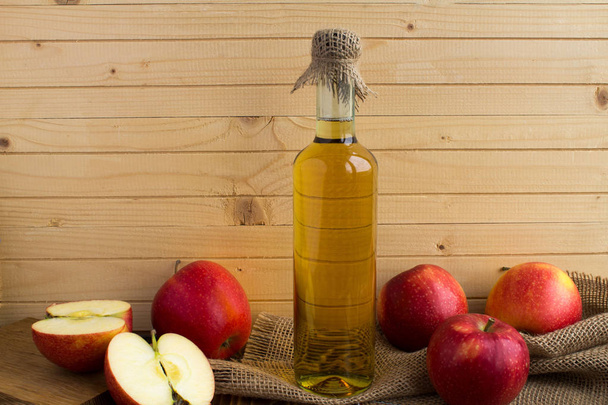 Vinaigre de pomme cidre dans la bouteille en verre sur le fond en bois brun clair
 - Photo, image