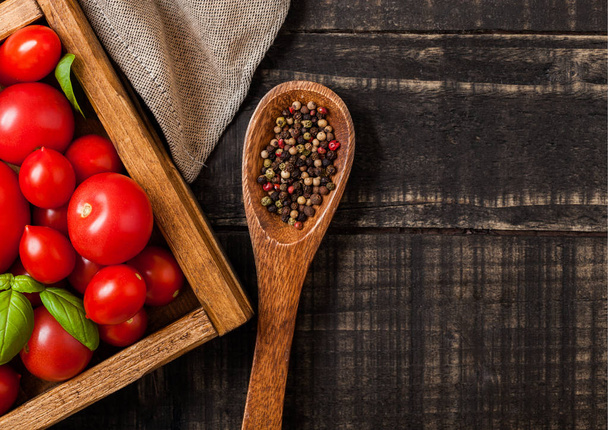 Organic Tomatoes with basil and pepper on spoon in vintage wooden box on wooden table - Valokuva, kuva