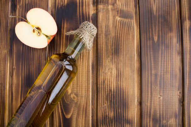 Appel azijn cider in de fles op de bruin houten achtergrond. Bovenaanzicht. Kopiëren van ruimte. - Foto, afbeelding