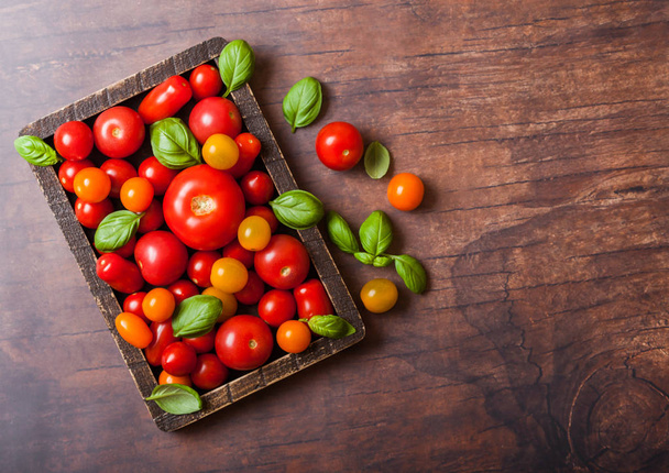 Organic Tomatoes with basil in vintage wooden box on wooden kitchen background. - Фото, зображення