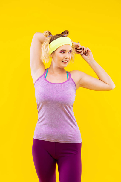 Woman wearing yellow head band stretching muscles - Foto, afbeelding