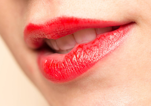 Close-up shot van vrouw lippen met glanzende rode lippenstift - Foto, afbeelding