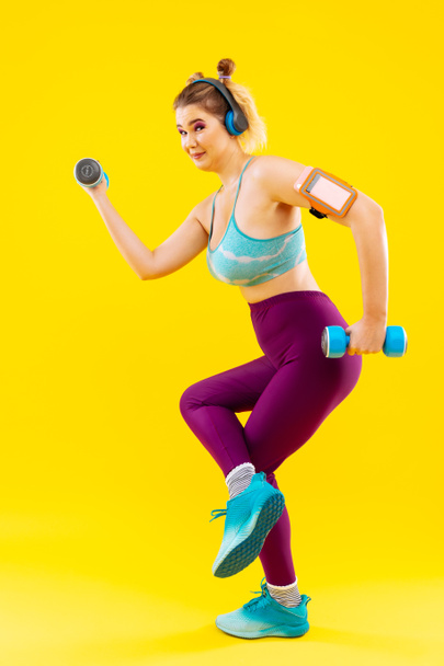 Woman wearing colorful clothes exercising with hand weights - Foto, afbeelding