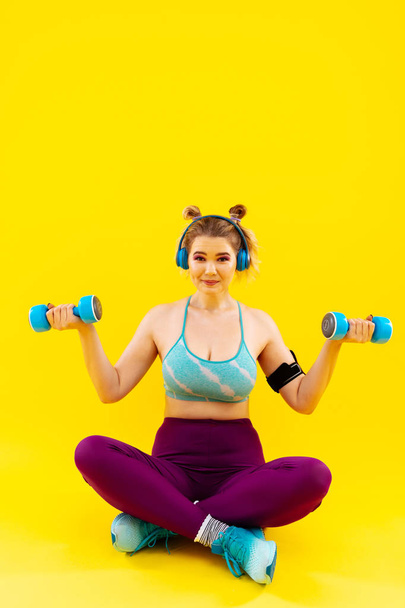 Young woman listening to music in earphones and exercising - Foto, afbeelding