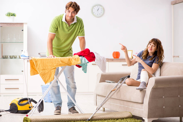 Marido ajudando perna ferida esposa em tarefas domésticas
  - Foto, Imagem