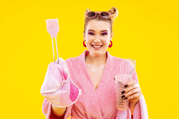 Smiling housewife with pink eye shades holding potholder - Zdjęcie, obraz