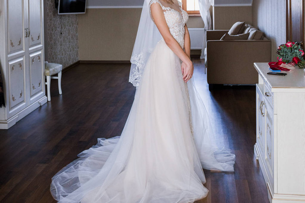 bride standing wearing wedding dress in room, cropped shot - Photo, image