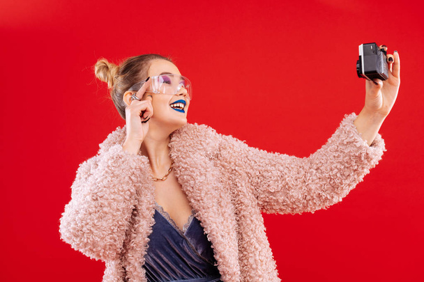 Woman wearing pink fluffy coat smiling while making selfie - Fotoğraf, Görsel