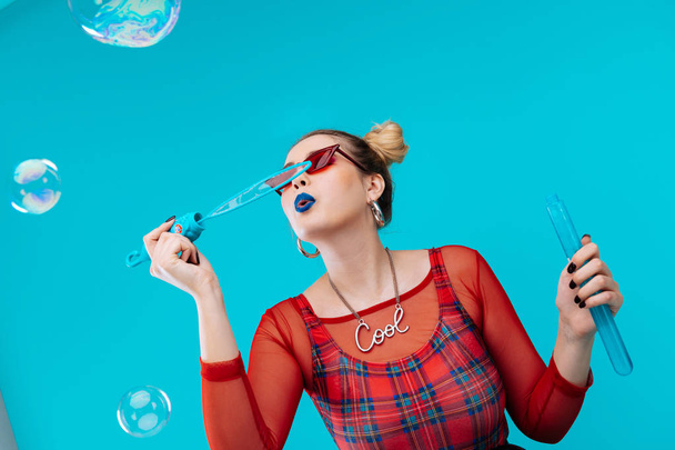 Woman with bright lips wearing nice necklace using soap bubbles - Fotoğraf, Görsel