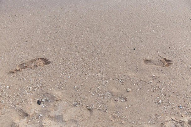 Πατημασιές στην άμμο στην παραλία, μερική θέα. - Φωτογραφία, εικόνα