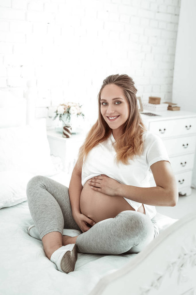 Positiivinen pitkätukkainen raskaana oleva nainen on tyytyväinen asemaansa
 - Valokuva, kuva