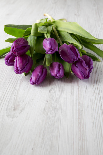 Tulipanes púrpura sobre superficie de madera blanca, vista lateral. Copiar espacio
. - Foto, imagen