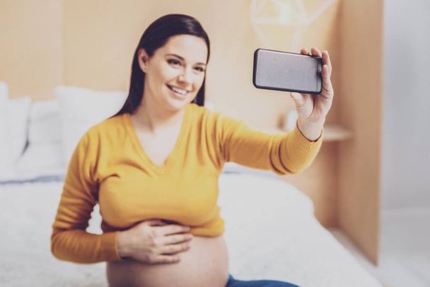 Charming future mother using her smartphone - Foto, Imagen