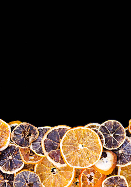 Frame of dry slices of grapefruit and orange. Fruit chips on black background. Festive Christmas or New Year design element. - Photo, image