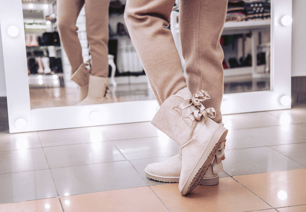 The girl try on in the store beautiful beige, winter boots. - 写真・画像