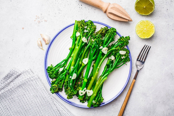 Boiled broccolini with garlic on a white plate. Plant based food concept. - Fotoğraf, Görsel