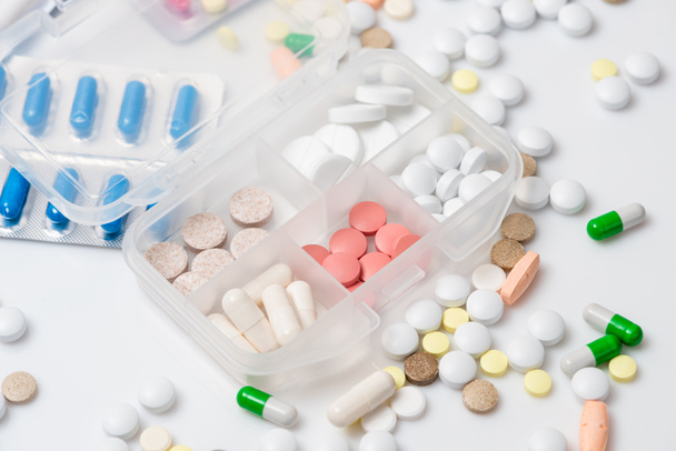 Close-up van pil zaak met verschillende kleurrijke medicijnen op witte achtergrond. - Foto, afbeelding