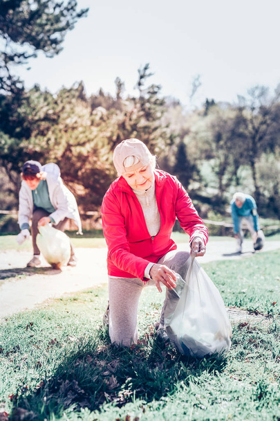Retired woman participating in clean the park campaign - Foto, imagen