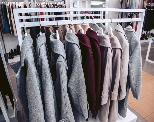 Une collection de manteaux d'automne pour femmes accrochés à un cintre dans un magasin de vêtements
. - Photo, image