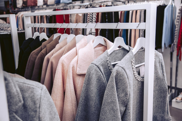 Una colección de costosos abrigos de primavera para mujer de varios colores en perchas en una tienda de ropa
. - Foto, Imagen