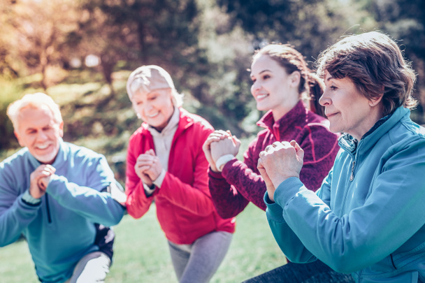 Femme retraitée aux cheveux bruns se joignant à ses amis faisant du sport
 - Photo, image