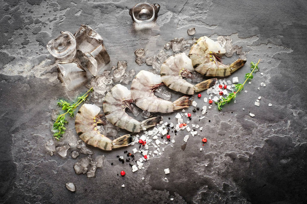 Raw tiger shrimps on gray stone top view with ice - Photo, Image