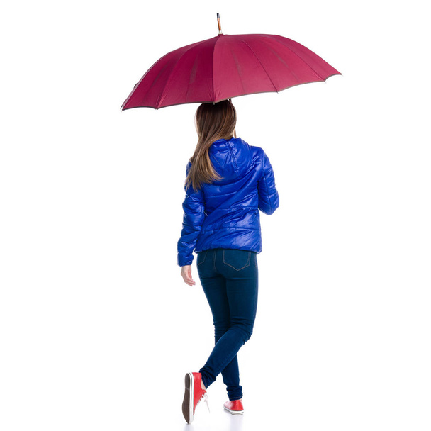 Woman in green jacket with umbrella in hand walking - Photo, image