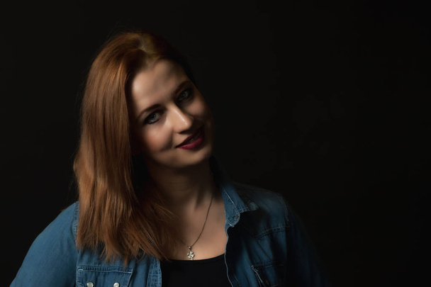 Low key portrait of smiling young attractive woman on the black background.  - Foto, imagen