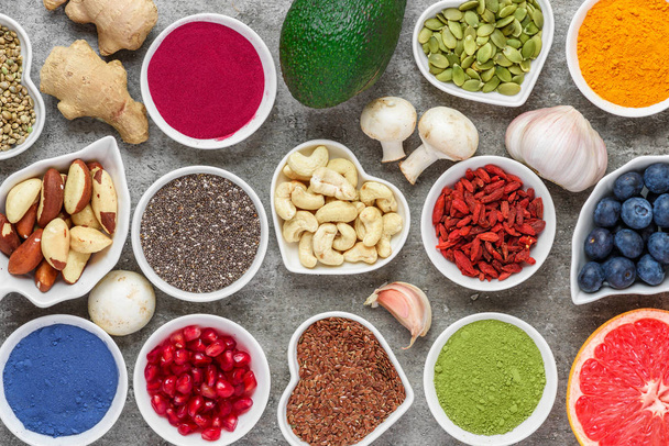 assortment of healthy vegan food on a gray background. matcha, acai, turmeric, fruits, berries, avocado, mushrooms, nuts and seeds. superfood top view - Photo, Image