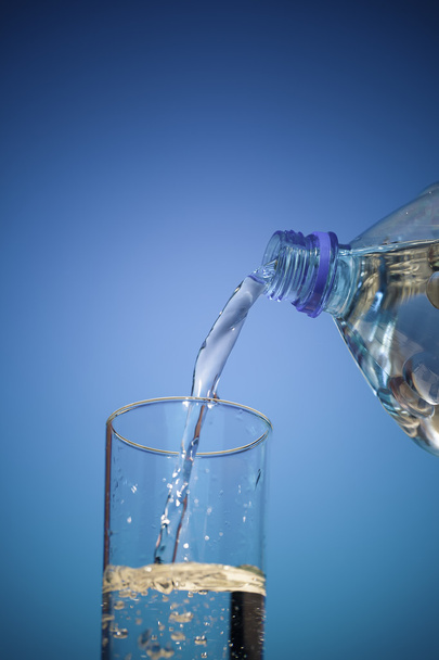 A água flui da garrafa para um copo
 - Foto, Imagem