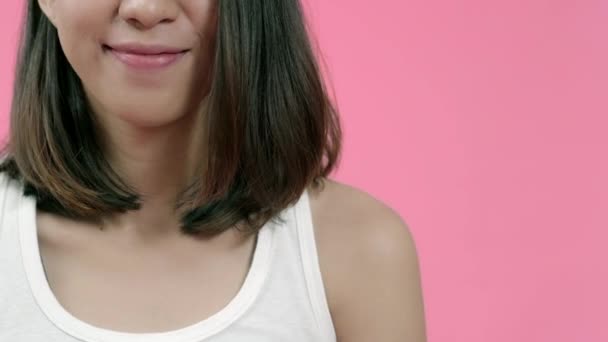 Femme asiatique adorable souriante avec une expression positive, sourit largement, vêtue de vêtements décontractés et regardant la caméra sur fond rose. Heureuse adorable femme heureuse se réjouit du succès
. - Séquence, vidéo