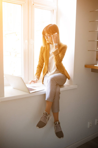 Beautiful woman designer freelancer in eyeglasses wearing casual using laptop in white office - Foto, Imagem