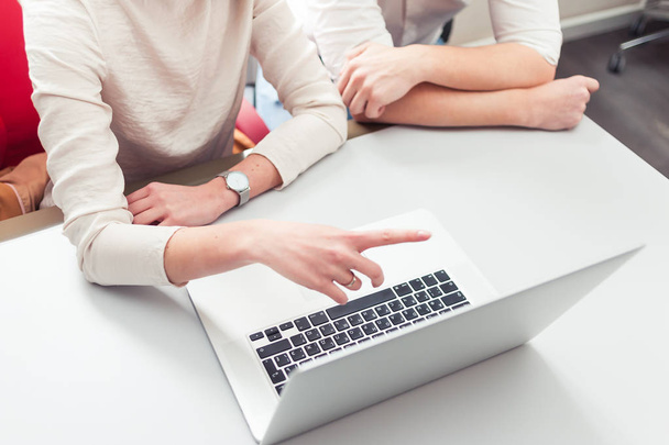 Dois jovens colegas de trabalho vestido casual usando laptop no interior branco
 - Foto, Imagem