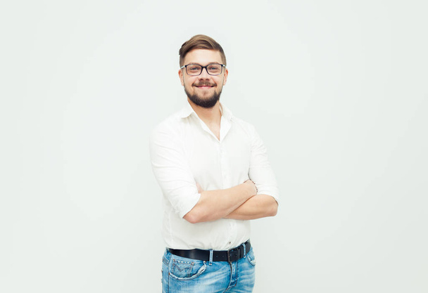 Portrait of a young man in glasses dressed in white shirt and casual clothes on a gray background - Photo, Image