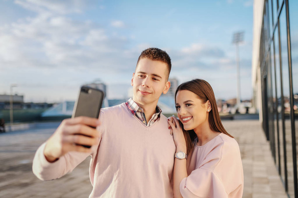 Joven pareja caucásica de moda tomando selfie en la azotea
. - Foto, Imagen