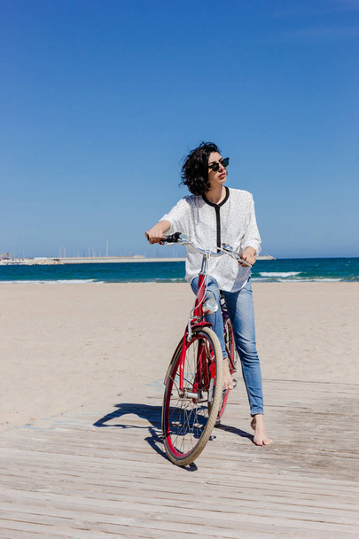 Smiling young woman with bicycle on a beach - Foto, Imagem