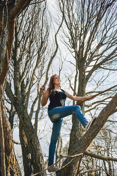 Young girl climbing a tree on a fine spring day - Fotó, kép