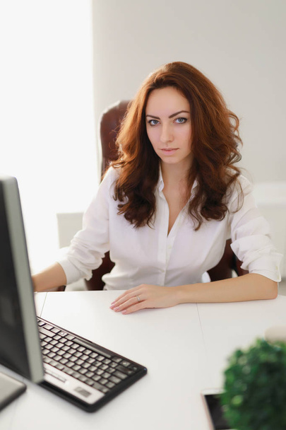 Beautiful businesswoman working in white office looking at camera - Foto, afbeelding