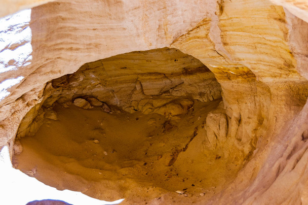 Forma redonda de cueva profunda en la roca de antiguas minas de cobre cañones y cordilleras en el Parque Nacional de Timna en Israel
 - Foto, imagen