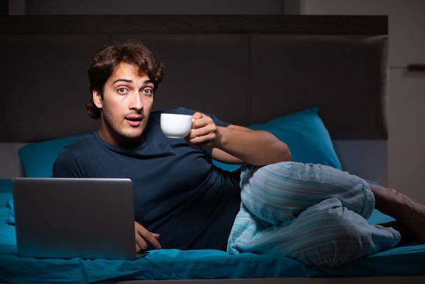 Man working on laptop at night in bed - Photo, Image