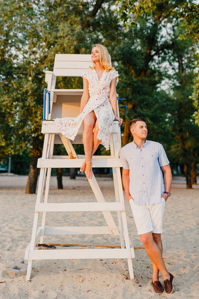 young couple posing at wooden construction in sunset light - Foto, imagen